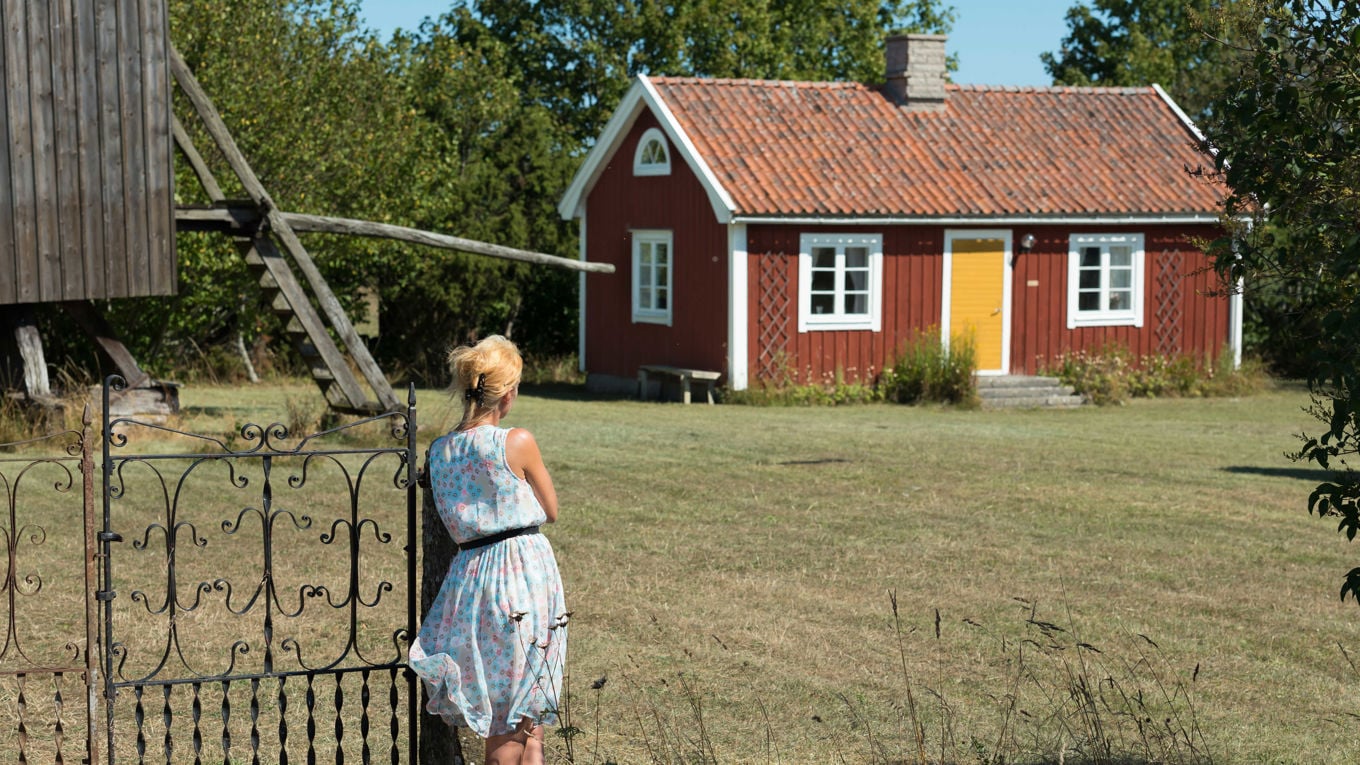 En kvinne ser mot en rød hytte