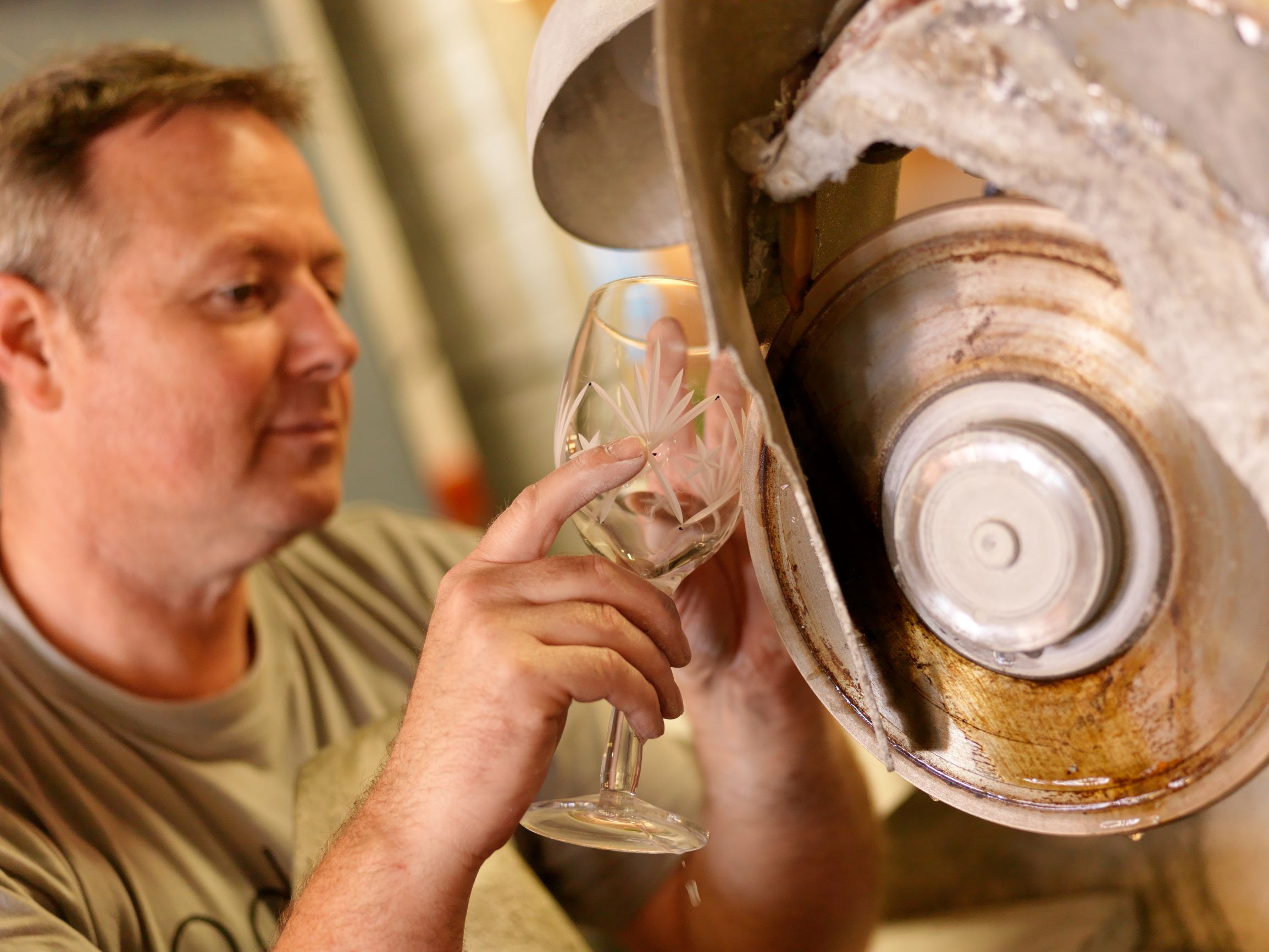 En mann pusser et krystallglass med en maskin