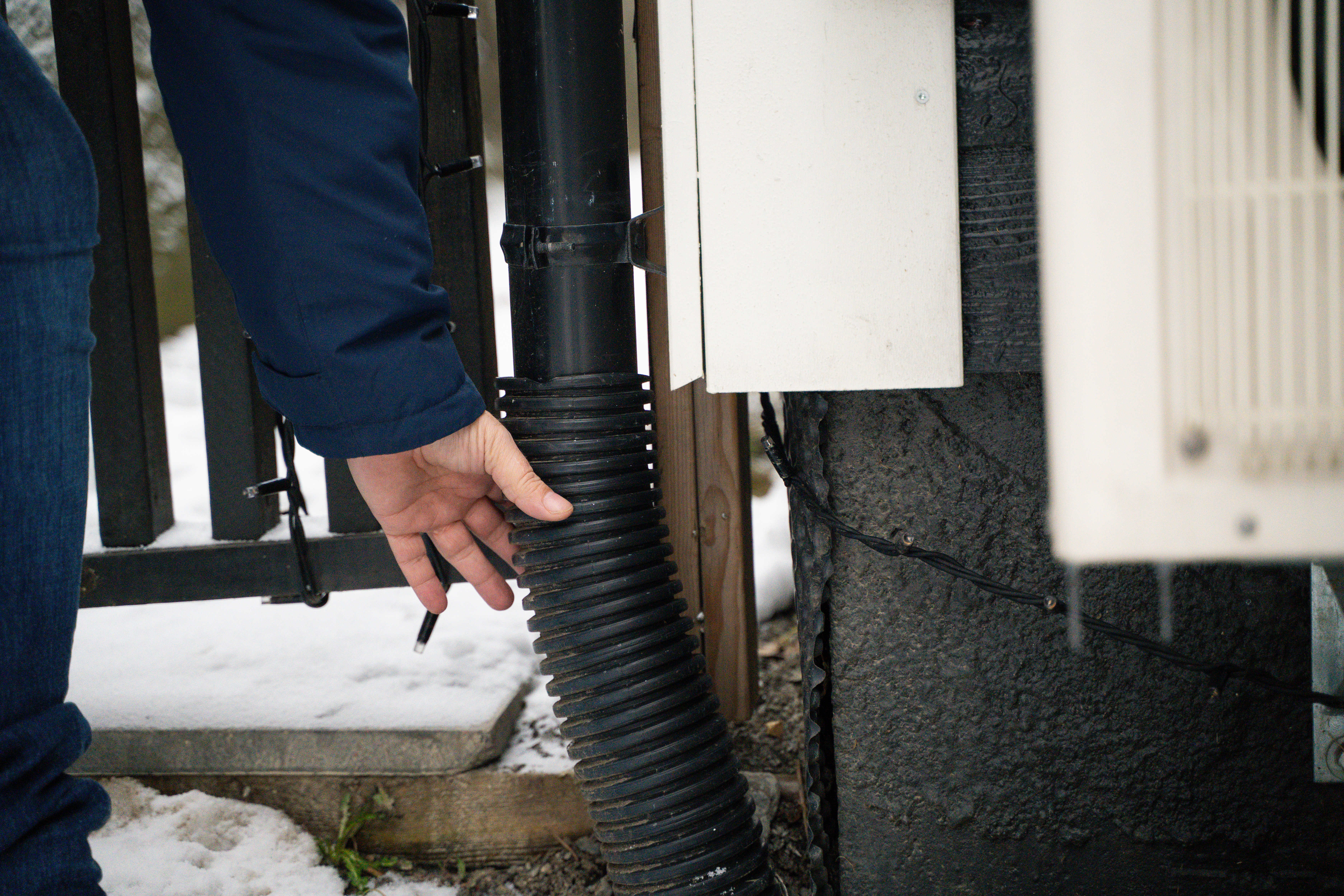 Noen holder i et fleksibelt rør koblet på en takrenne