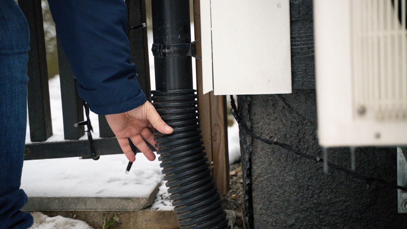 Noen holder i et fleksibelt rør koblet på en takrenne