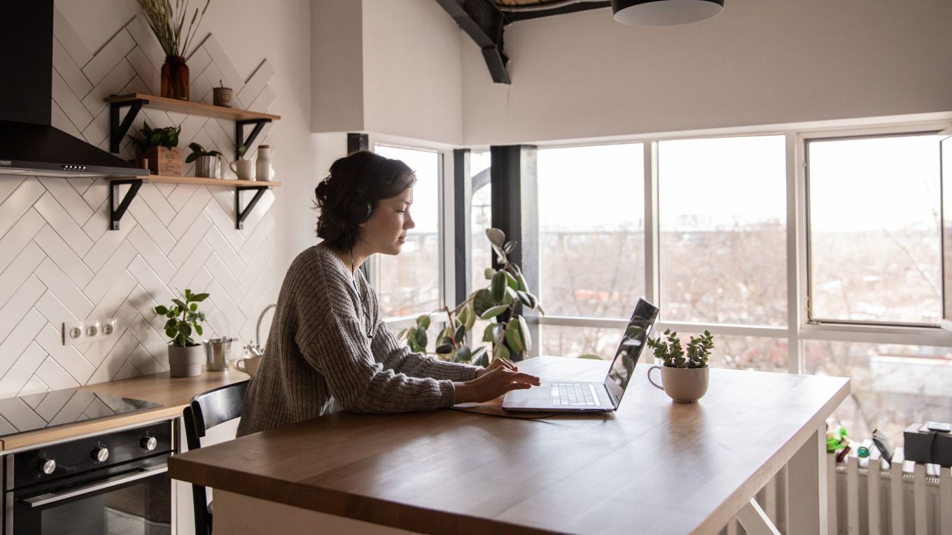 Kvinne sitter hjemme foran datamaskinen sin