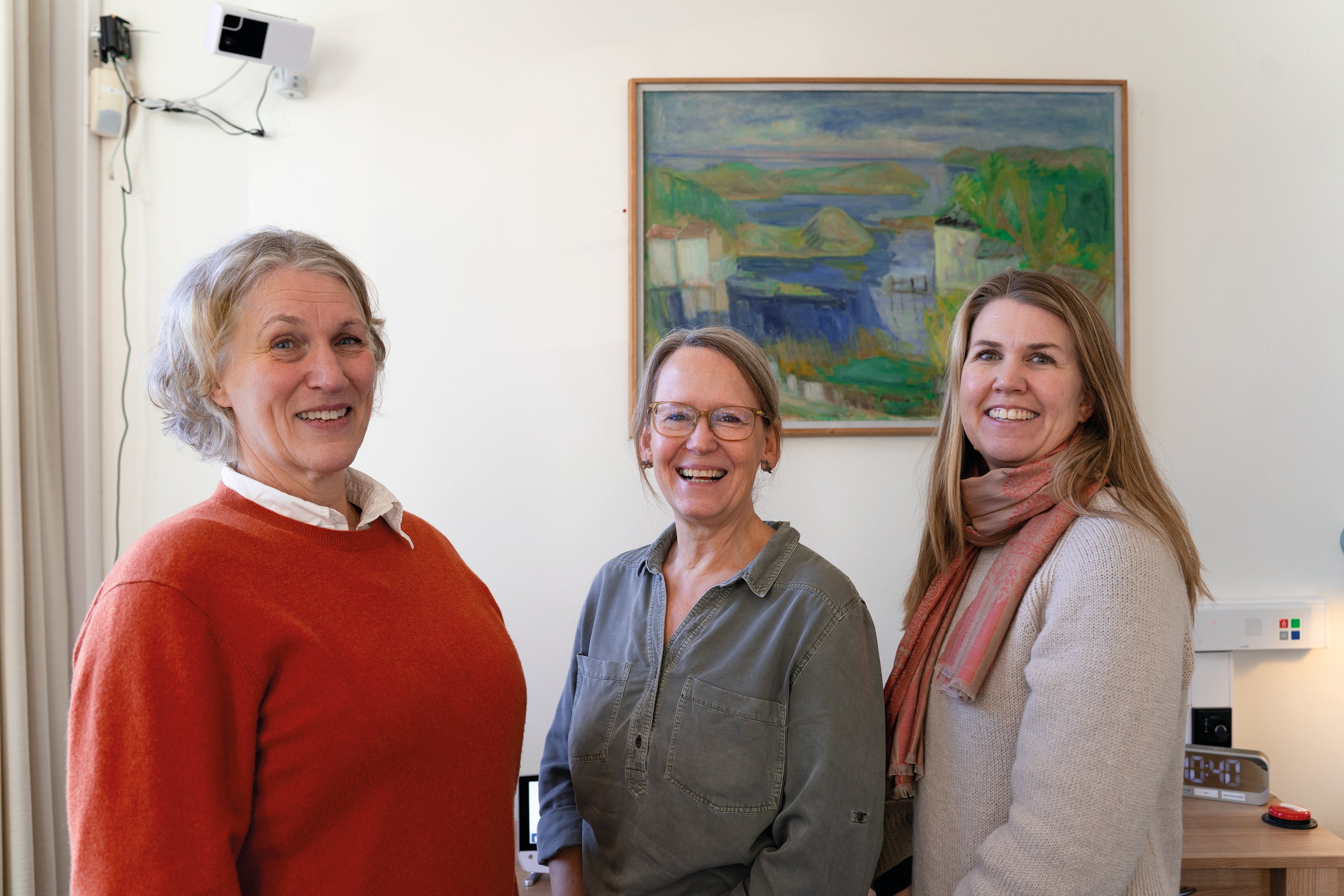 Tre kvinner smiler mot kamera
