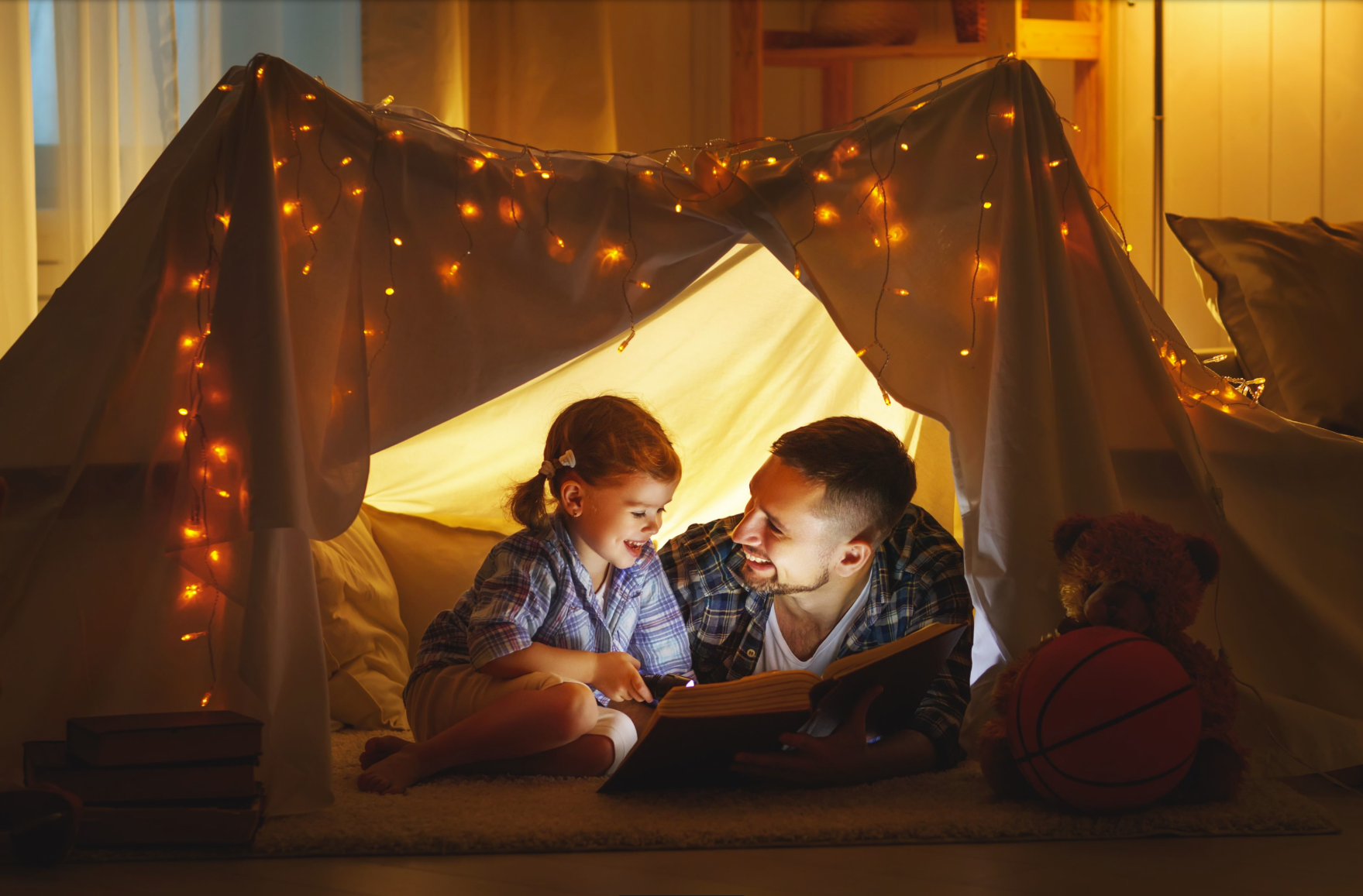 En jente og en mann leser bok i et telt i stuen