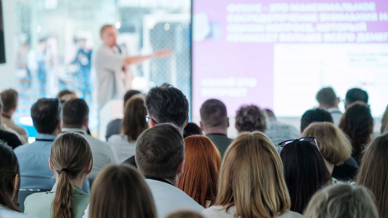 Flere mennesker ser mot en mann som presenterer
