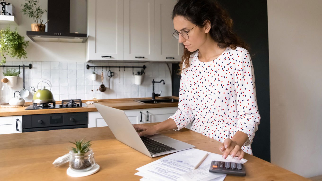Kvinne ved kjøkkenbordet med en laptop