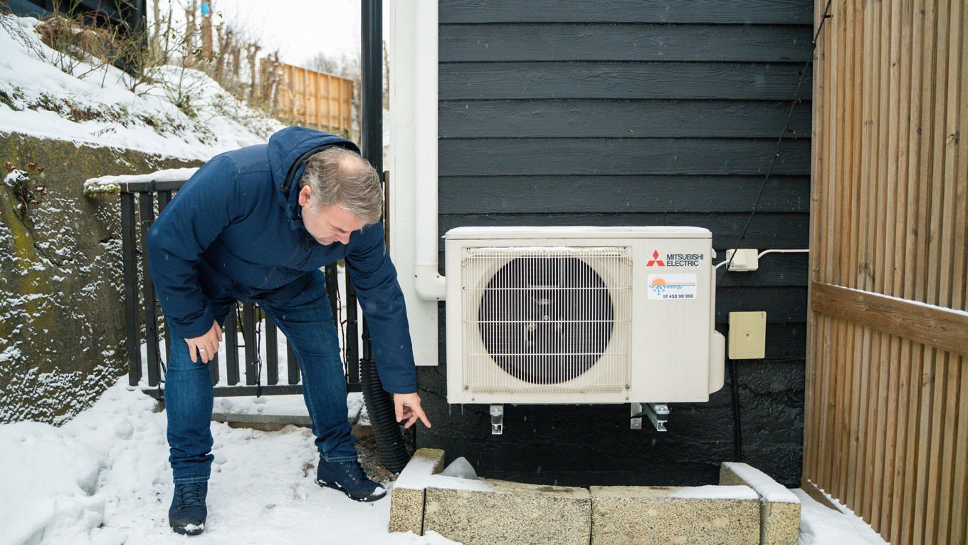 Anders Stensrud peker på en varmepumpe på en husvegg