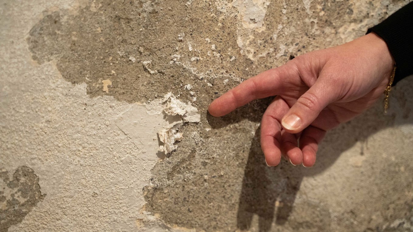 En hånd peker mot saltkrystaller på en vegg