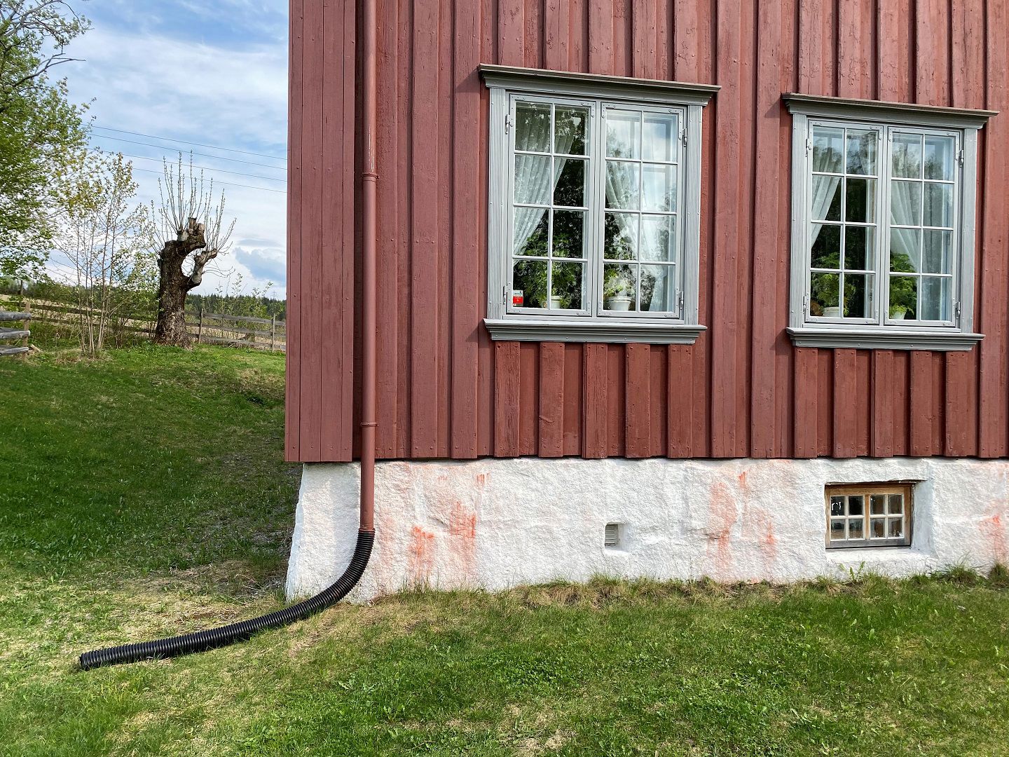 Et bøyelig plastrør festet på taknedløpet, leder takvannet vekk fra boligen.