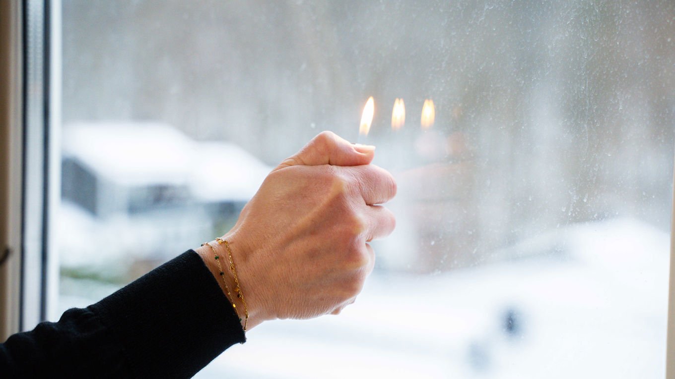 En lighter brenner foran et vindu