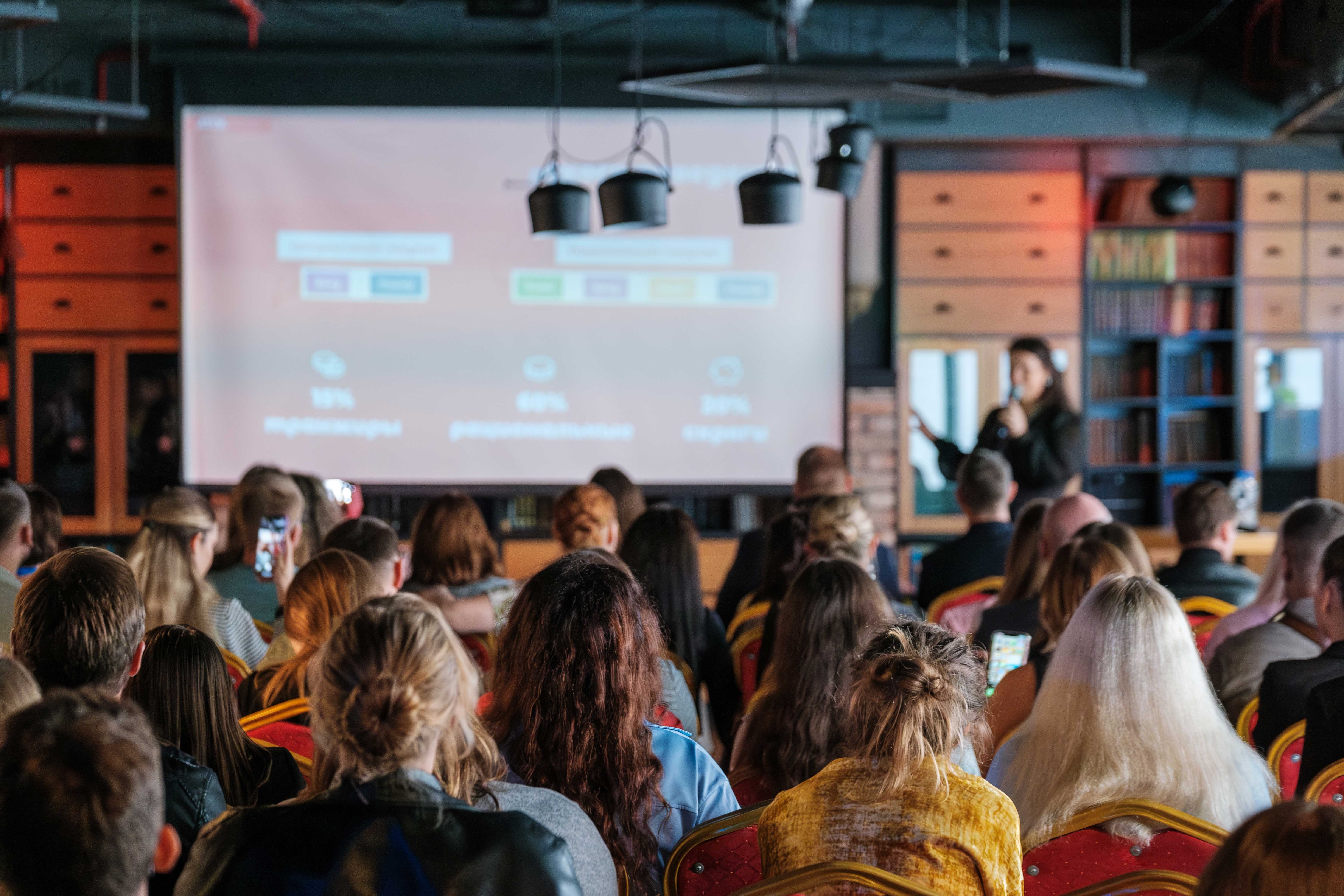 Mange mennesker på et møte ser mot en skjerm med en presentasjon