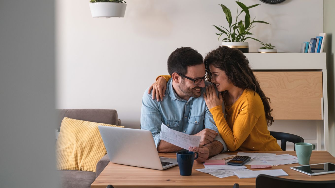Et samboerpar som omfavner hverandre på sofaen