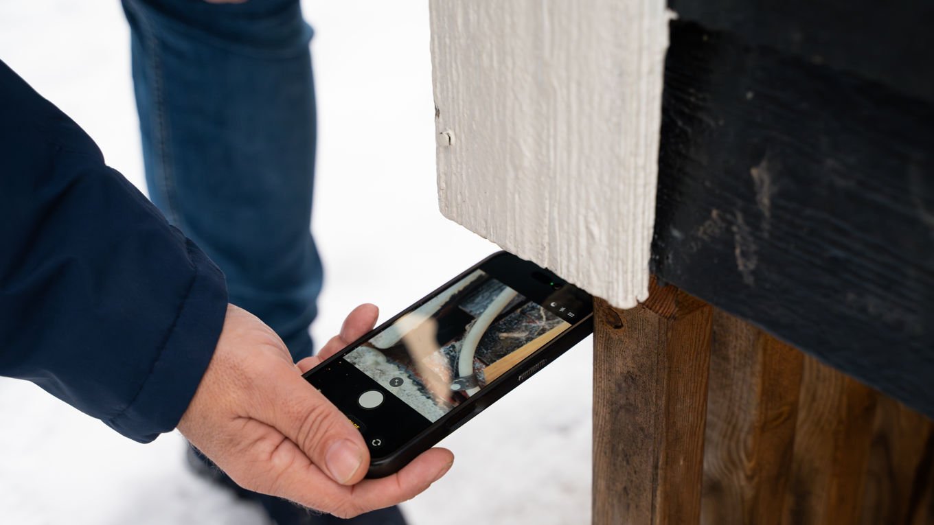 En mobil brukes til å sjekke under et ytterpanel