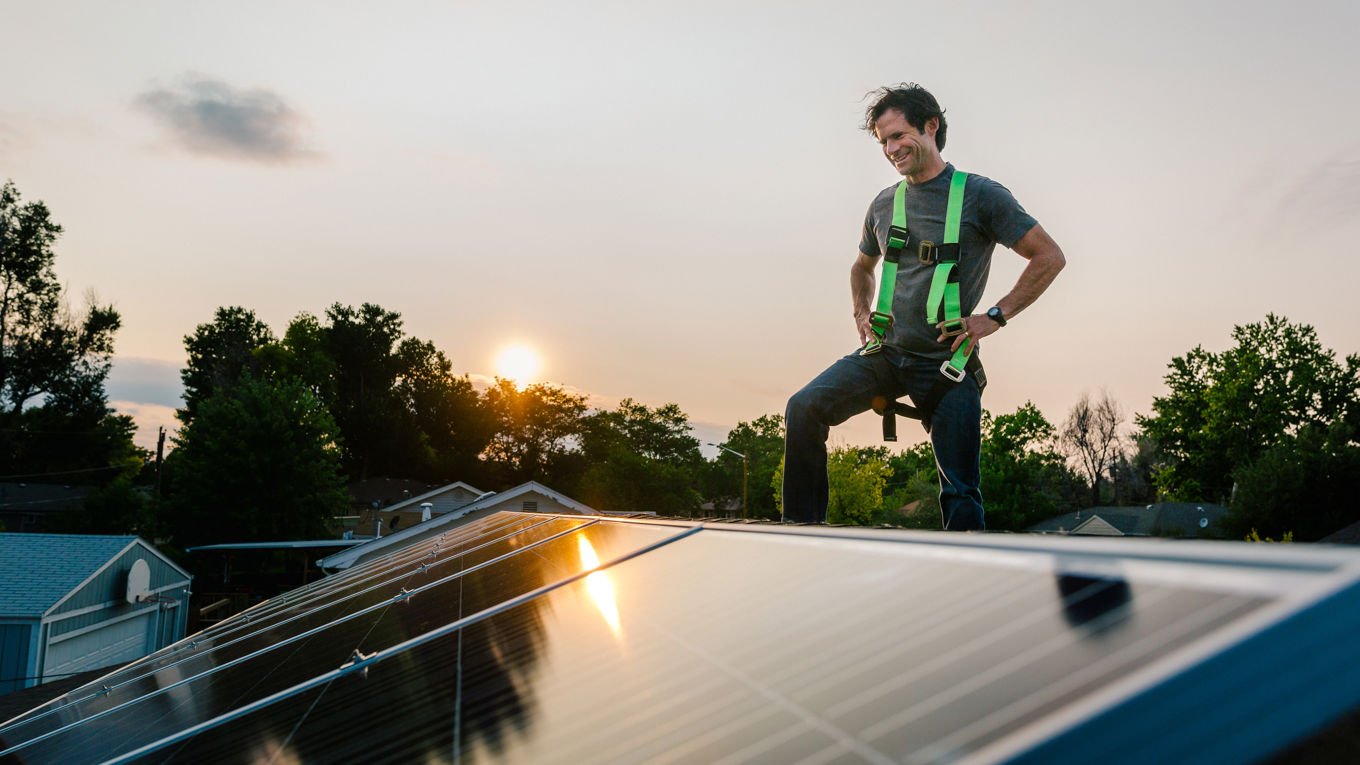 Mann på et tak fullt av solcellepanel